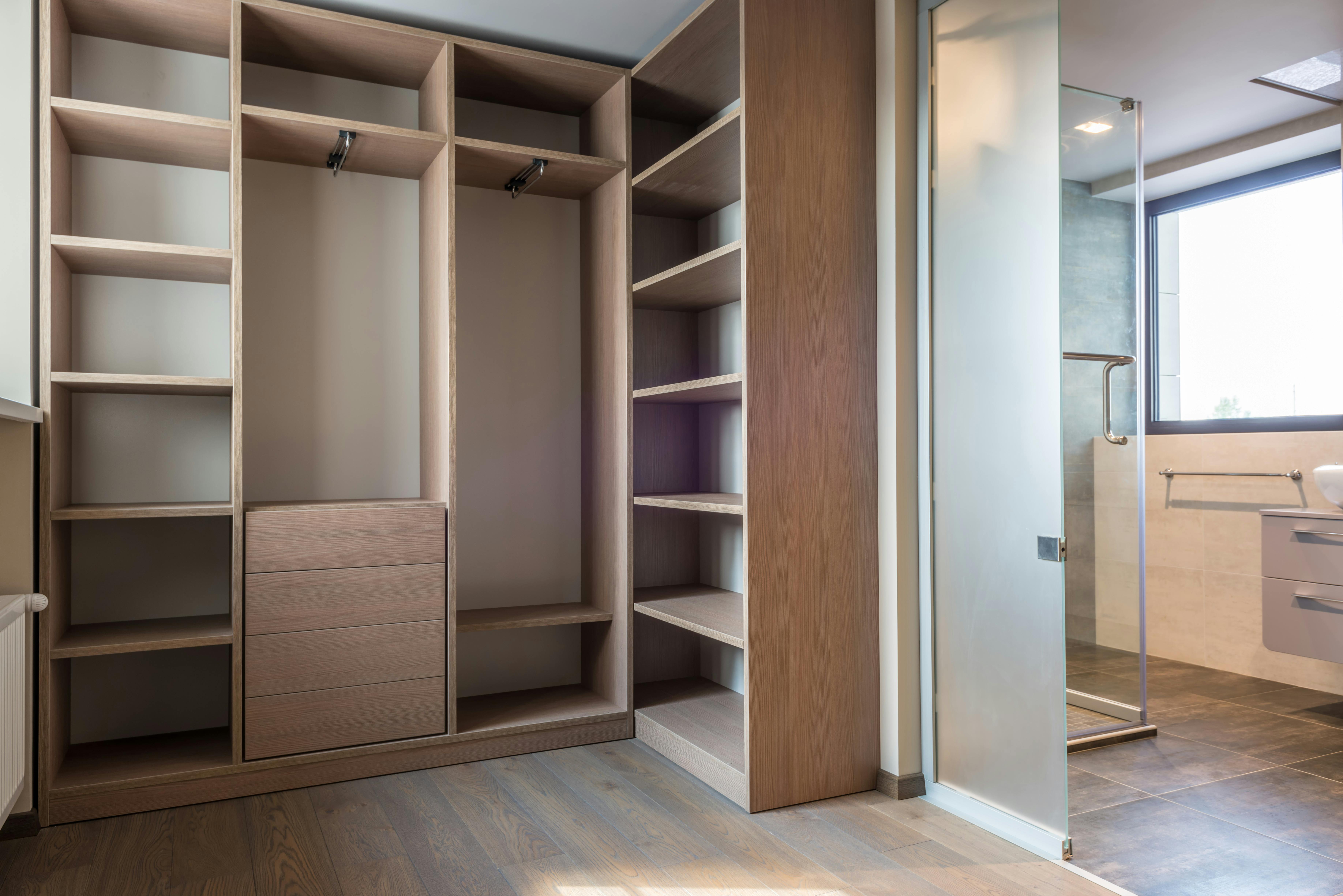 Walk-in closet with built-in shelves, drawers, hanging sections, and organized layout next to ensuite bathroom